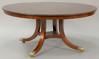 Custom round mahogany table with pedestal base set on four downswept members ending in brass paw feet, opens round with attachable l...