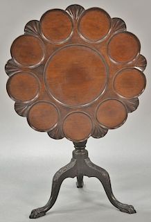 George II mahogany tip table having shaped top with ten circular panels on carved shaft set on tripod base with carved ball and claw...