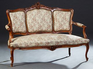 French Louis XV Style Carved Walnut Settee, early 20th c., the arched C-scroll and floral carved crest rail, over three upholstered panels, within uph