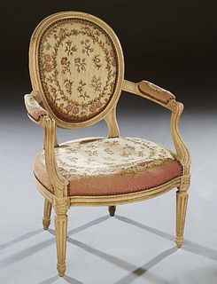 French Polychromed Beech Louis XVI Style Fauteuil, 20th c., the oval upholstered back flanked by upholstered arms and a bowed upholstered seat, on tur