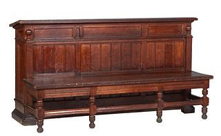 French Oak Courthouse Bench, late 19th c., the slanted top over a raised tongue and groove panel back with ball finials, over a wide skirt, with urn a