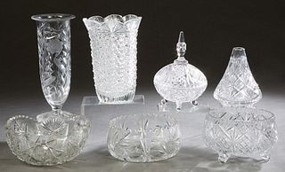 Seven Pieces of Cut Glass, 20th c., consisting of a tapered scalloped cylindrical example; a footed example, a covered box; a tapered short vase, two 