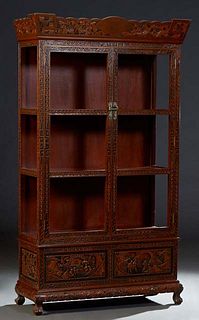 Chinese Carved Mahogany Display Cabinet, 20th c., the arched canted floral carved crown, over double three panel glazed doors, above scenic relief fig