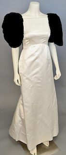 Arnold Scaasi, c. 1985, Evening gown of cream silk satin, with black velvet puffed sleeves. Arched waistline; large satin bow on skirt behind knees. E