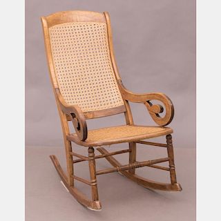 An American Walnut Rocking Chair with Caned Seat and Back, 19th Century.