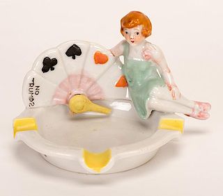 Trump Indicator Girl. Circa 1930. Porcelain ash tray made either in Japan or Germany. Tiny chip on tip of pointer, otherwise excellent.
