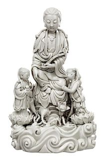 A BLANC-DE-CHINE FIGURE OF GUANYIN ON A ROCK WITH TWO ATTENDANTS
