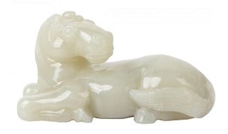 A CHINESE PALE CELADON JADE CARVING OF A RECLINING HORSE