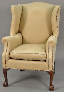 Tan upholstered wing chair with ball and claw feet.