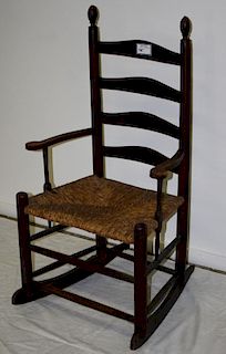 Early ladder-back armed finial top rocking chair in original dark red surface, rush seat, probably P