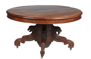 French Carved Oak Henri II Dining Table, c. 1880, the stepped oval top on a large square support flanked by three gryphon carved splayed legs, opening