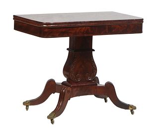American Carved Mahogany Games Table, late 19th c., the rounded corner top swiveling over open storage above a wide skirt, on a lyre form support to f