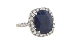 Lady's 18K White Gold Dinner Ring, with an oval 10.02 ct. blue sapphire atop a border of round diamonds, the shoulders of the band also mounted with r