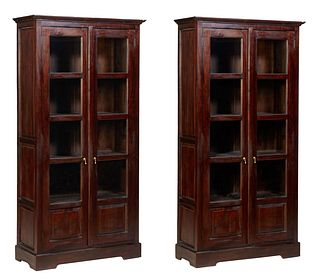 Pair of Tall Indonesian Carved Mahogany Bookcases, 20th c., the stepped top over long double doors with mullioned glazed upper panels over fielded woo