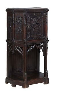 French Carved Oak Gothic Revival Cabinet, 19th c., the hexagonal ogee edge top over a cupboard door with wrought iron strap hinges and latch flanked b