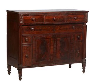 American Classical Carved Mahogany Sideboard, 19th c., the thick reeded edge rectangular top over three frieze drawers above double cupboard doors fla