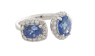 Unusual Lady's 18K White Gold Dinner Ring, the open band terminating in an oval vertical blue sapphire atop a diamond mounted border on one end and an