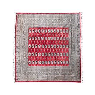 TAPETE. PAKISTÁN, SXX. Estilo BOKHARA. Elaborado en fibras de lana. Con fondo en color rojo y elementos orgánicos y vegetales.