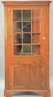 Cherry custom made corner cabinet having one glass door over one drawer over double bottom doors, top fitted with cut shell shaped...