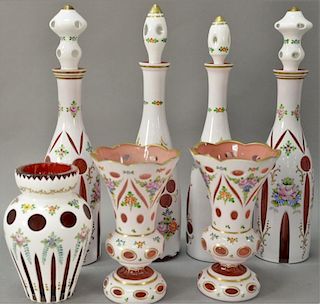 Group of seven white cut to cranberry glass pieces including two pairs of tall decanters, and pair of vases.
