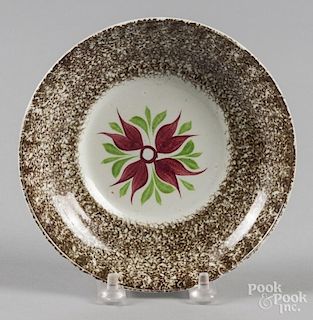 Brown spatter saucer with a four-petal flower decoration.