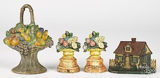 Three painted cast iron flower basket doorstops, together with a house doorstop, tallest - 10 1/2''.