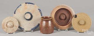 Four stoneware lids, 19th c., together with a merchant's crock, largest - 9'' dia.