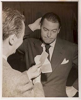 Vernon, Dai. Portrait of Dai Vernon performing for Chester Morris. Circa 1948. Oversize image of Vernon, back to the camera, performing a card trick f