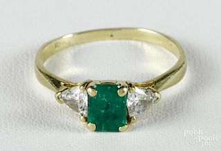 18K yellow gold ring with a central rectangular cut emerald flanked by two triangular cut diamonds