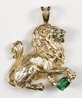 14K yellow gold lion pendant with an emerald eye and an emerald under paw, 1 3/8'' h., 7.0 dwt.