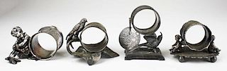 lot of 4 silver plated figural napkin rings incl; child putting on shoes, cherubs, birds