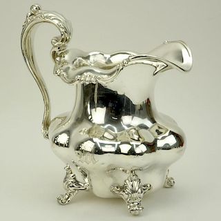 Large Durgin Sterling Silver pitcher. Features foliate handle and scroll feet.