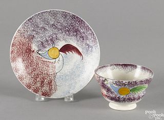 Red, blue, and purple rainbow spatter cup and saucer with peafowl decoration.