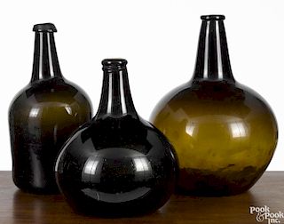 Three early olive amber glass bottles, 19th c., 11 1/2'' h., 13 1/4'' h., and 14'' h.