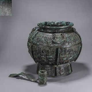 A taotie patterned bronze pot with a spoon