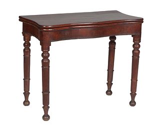 American Victorian Carved Mahogany Games Table, late 19th c., the serpentine top over open storage, and a serpentine skirt, on turned tapered cylindri