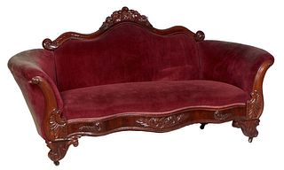 American Victorian Carved Mahogany Settee, 19th c., the arched serpentine floral carved crest rail over a cushioned back and rolled cushioned scrolled