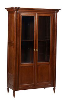 French Louis XVI Style Carved Walnut Bookcase, 19th c., with a top plinth over the stepped crown above double doors with glazed upper panels over wood