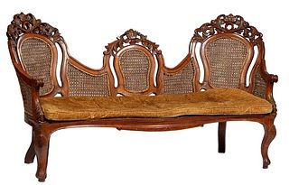 French Louis XV Style Carved Walnut Triple Chairback Caned Settee, early 20th c., the arched pierced scroll, floral and leaf carved crests over double