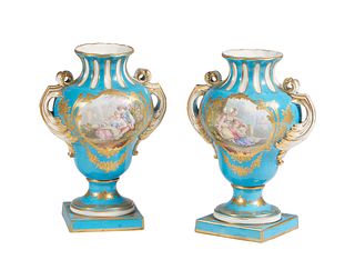 Pair of Sevres Style Porcelain Baluster Handled Urns, 20th c., in heavenly blue with gilt decoration and reserves of lovers in a garden on one side an