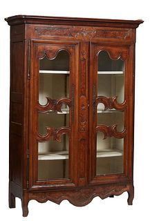 French Carved Walnut Louis XV Style Bookcase, 19th c., the stepped rounded corner crown over a floral basked carved frieze above double three panel gl