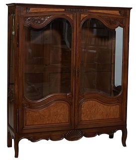 French Louis XV Style Carved Oak and Walnut Vitrine, 20th c., the stepped rounded corner top over double doors with wide beveled glazed upper panels o