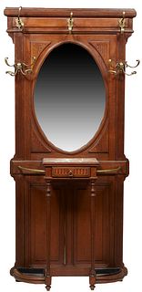 French Carved Oak Hall Stand, early 20th c., the stepped crown over double brass hat hooks over an oval wide beveled mirror, flanked by two large bras