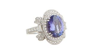 Lady's Platinum Dinner Ring, with a 4.41 carat oval tanzanite atop a conforming double concentric border of tiny round diamonds flanked by diamond win