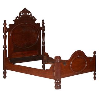 American Victorian Carved Walnut Highback Double Bed, late 19th c., the arched pierced scrolled leaf carved crest over a headboard with an oval panel,