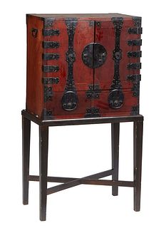 Japanese Iron Bound Carved Pine Tansu on Stand, 20th c., with double cupboard doors over two lower frieze drawers, the sides with folding iron handles