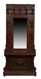 French Carved Oak Hall Tree, c. 1900, the stepped ogee crown over five carved wooden double coat hooks, over a rectangular mirror flanked by four larg
