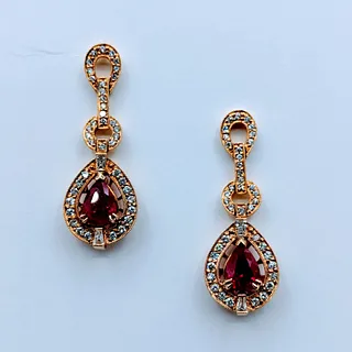 These spectacular ruby earrings are crafted in 14kt yellow gold and feature .89ctw round white diamonds, SI1-SI2 clarity and G-H color. These drop ear
