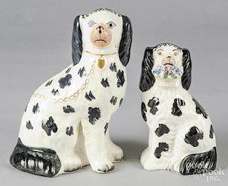 Two Staffordshire spaniels, one with a basket of flowers, 9 1/2'' h. and 8'' h.