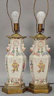 Pair of famille rose porcelain urns having hexagon body with painted panels of Guanyin and scholars, molded foo dog handles, and dra...